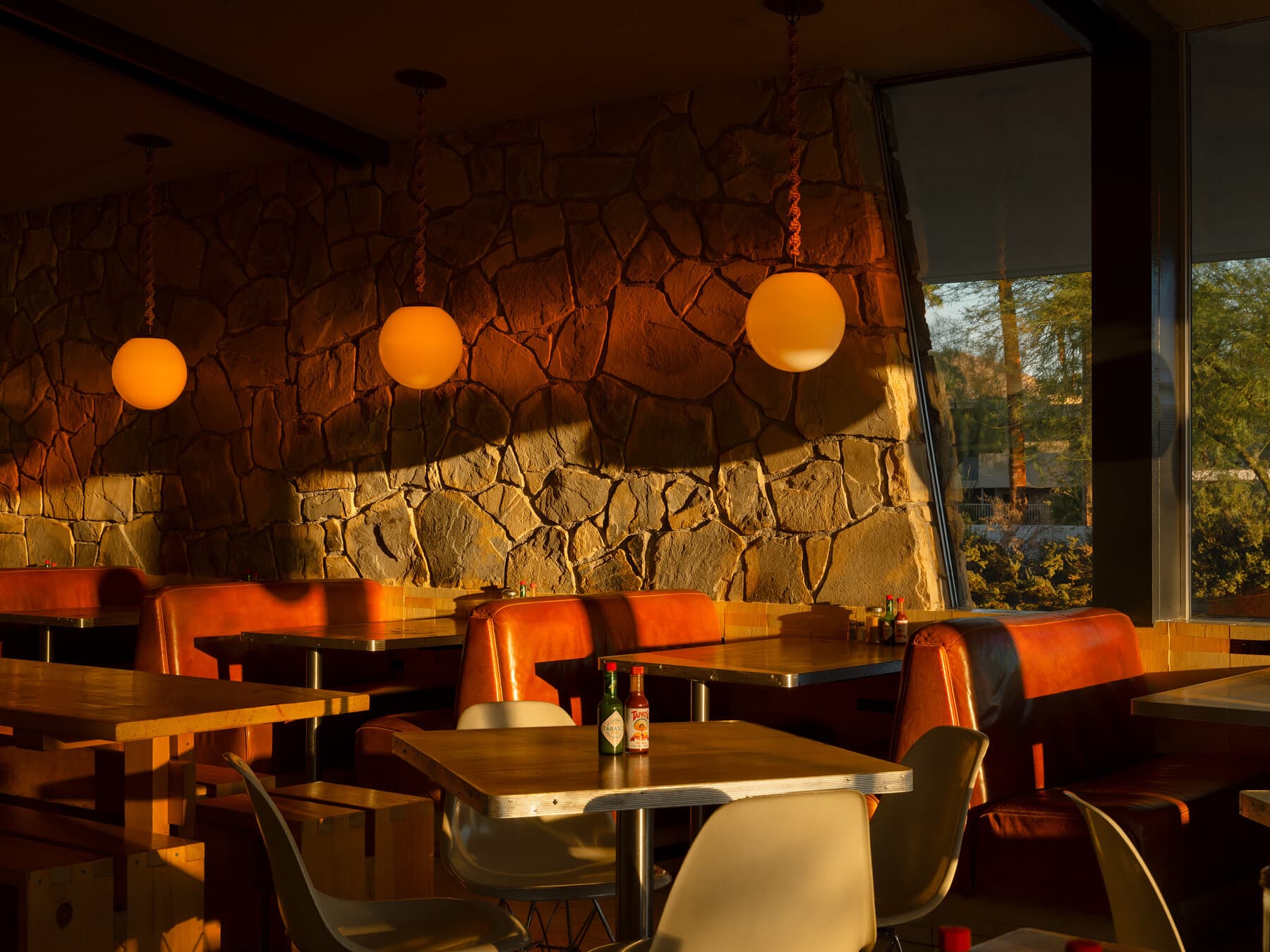 Rough-cut stone feature wall and globe pendant lights in the King's Highway diner at golden hour