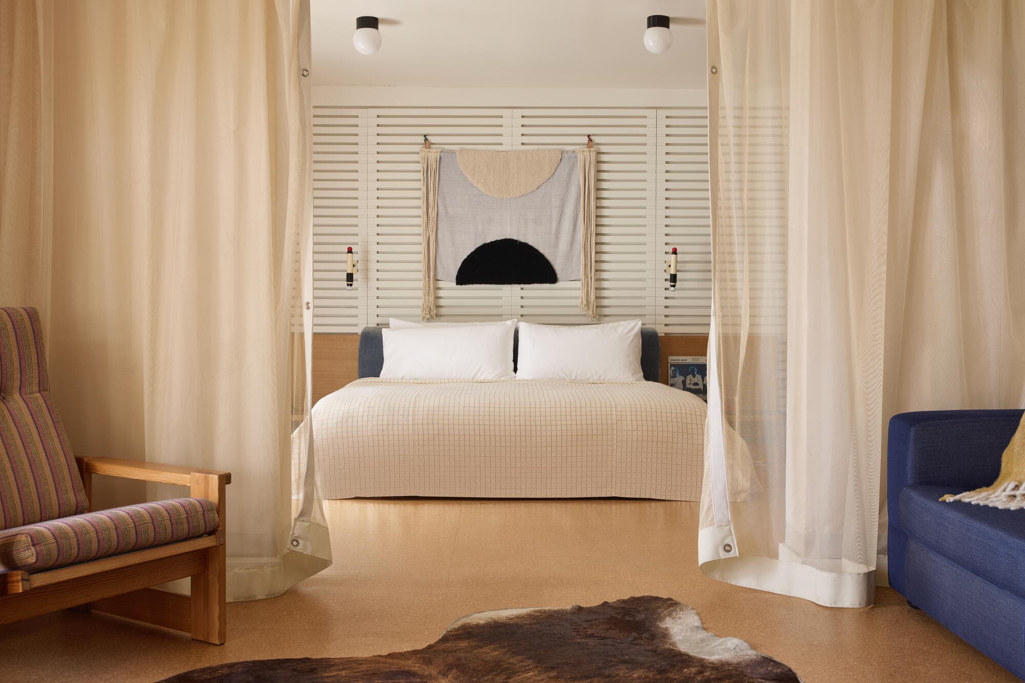 Ace Hotel guest room with a slatted wood headboard wall, woven textile art and cork floor