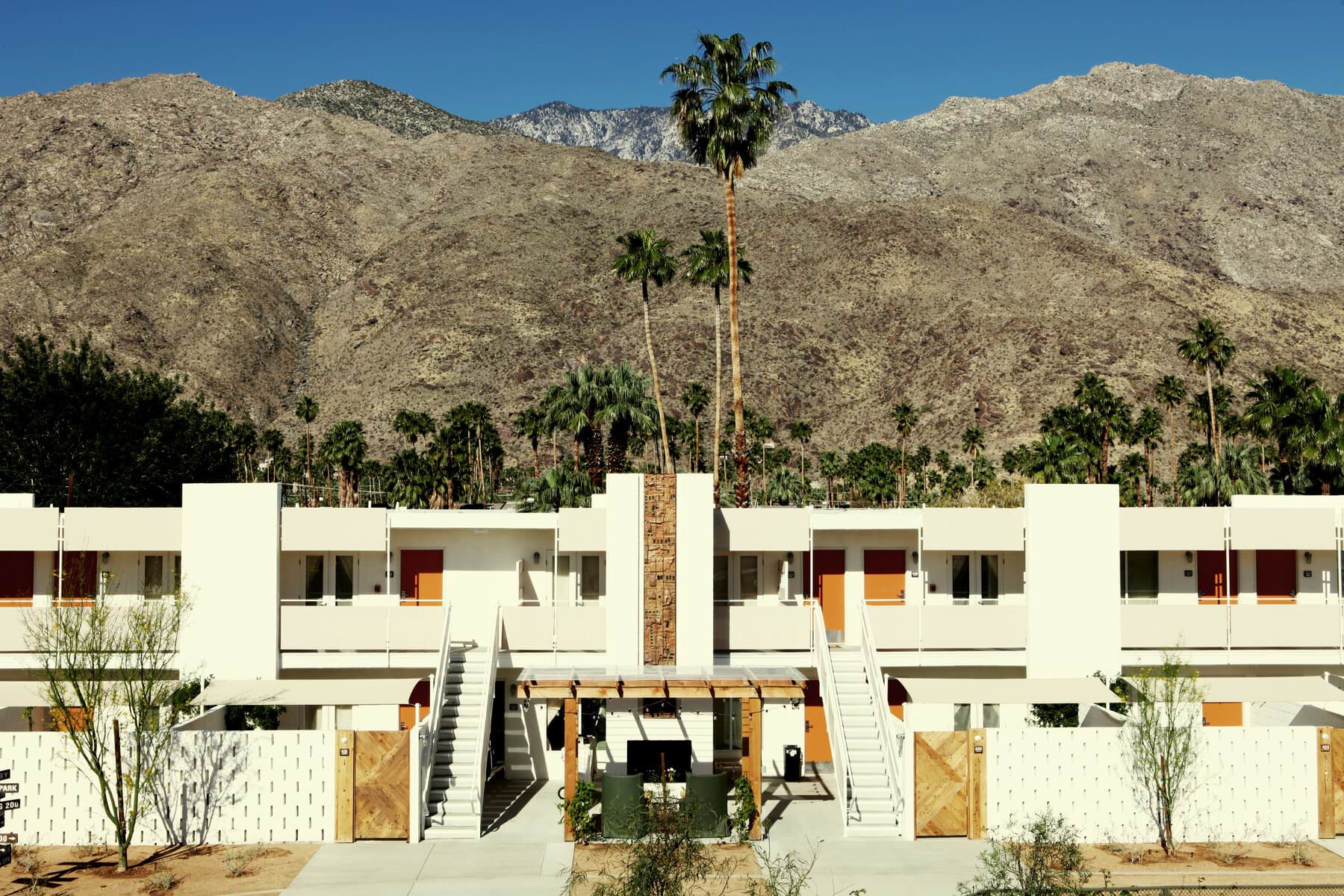 Ace Hotel room block with twin exterior stairs and a stone-clad chimney against the mountains