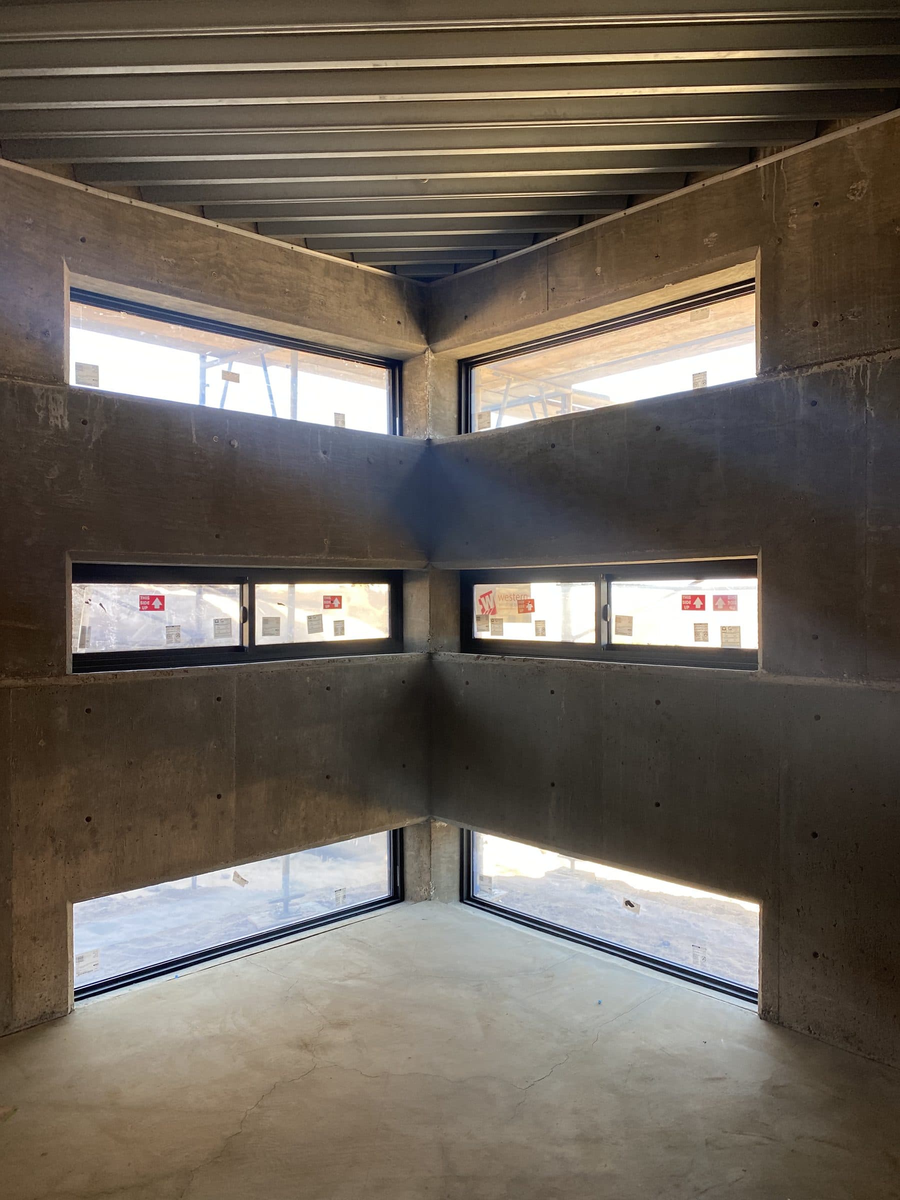 Symmetrical interior corner of stacked clerestory windows, newly glazed, manufacturer stickers still on the glass.
