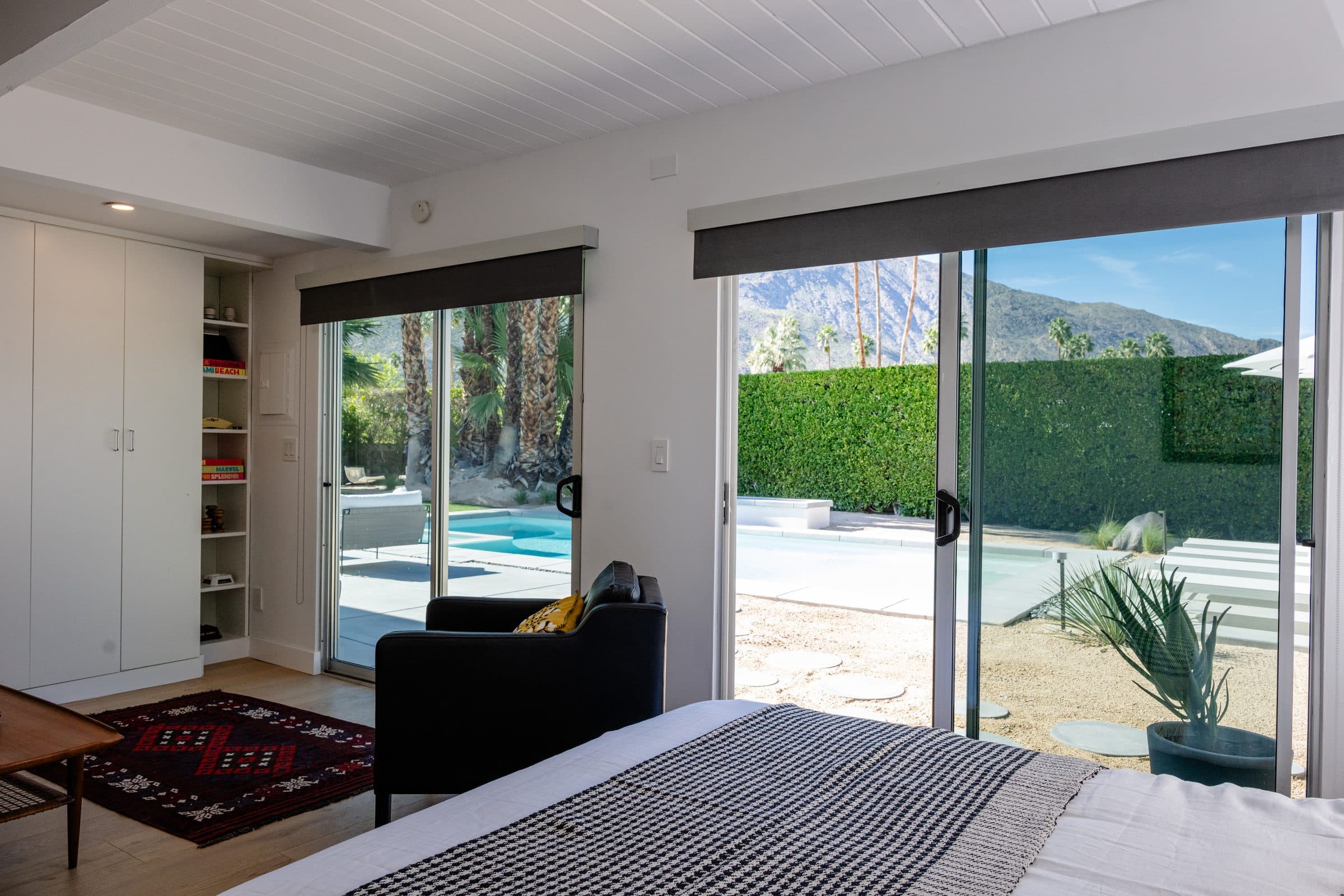 Sliding glass doors beside the bed, garden light falling across the covers.