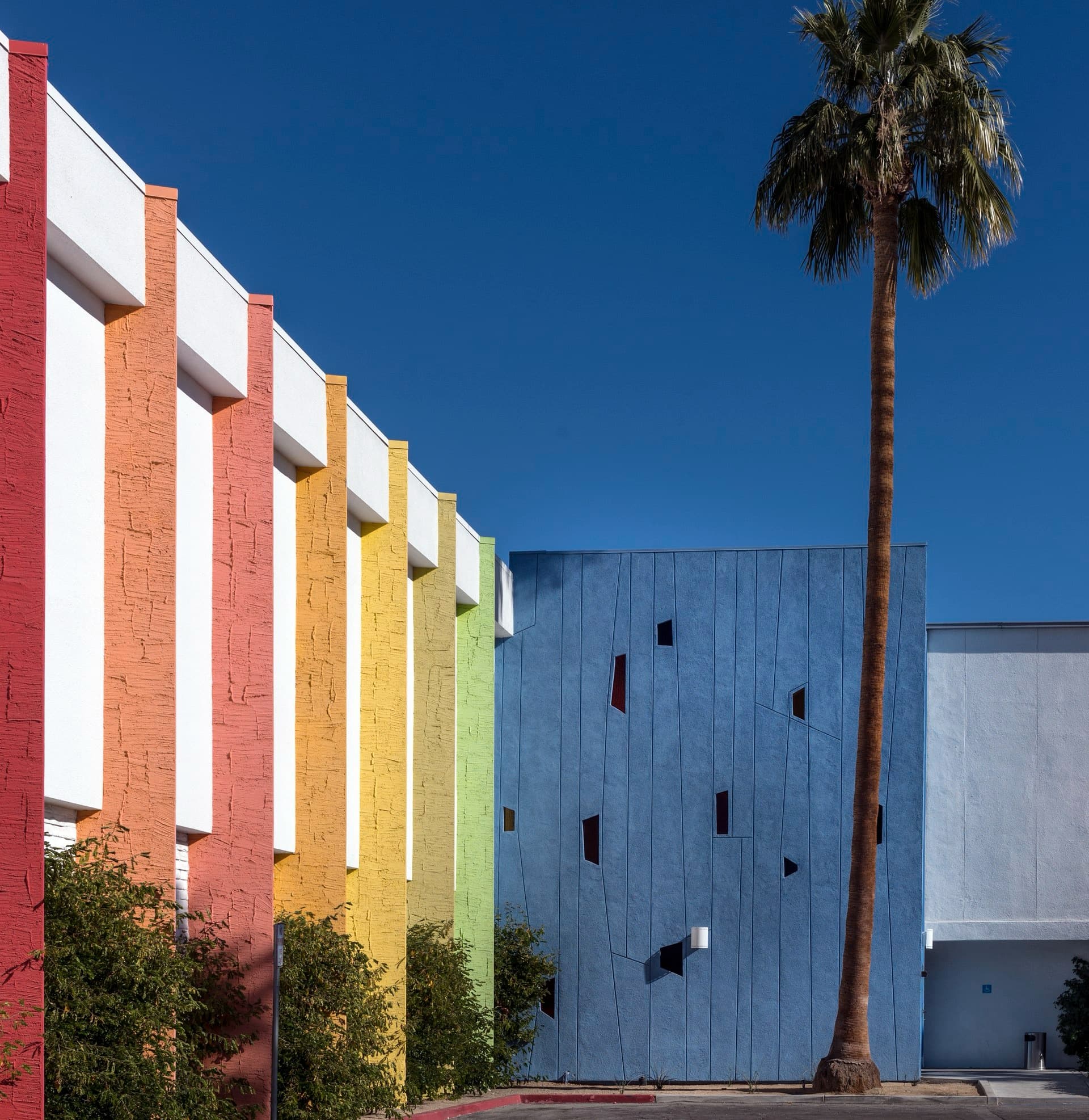 The colorful striped façade of the Saguaro with a palm