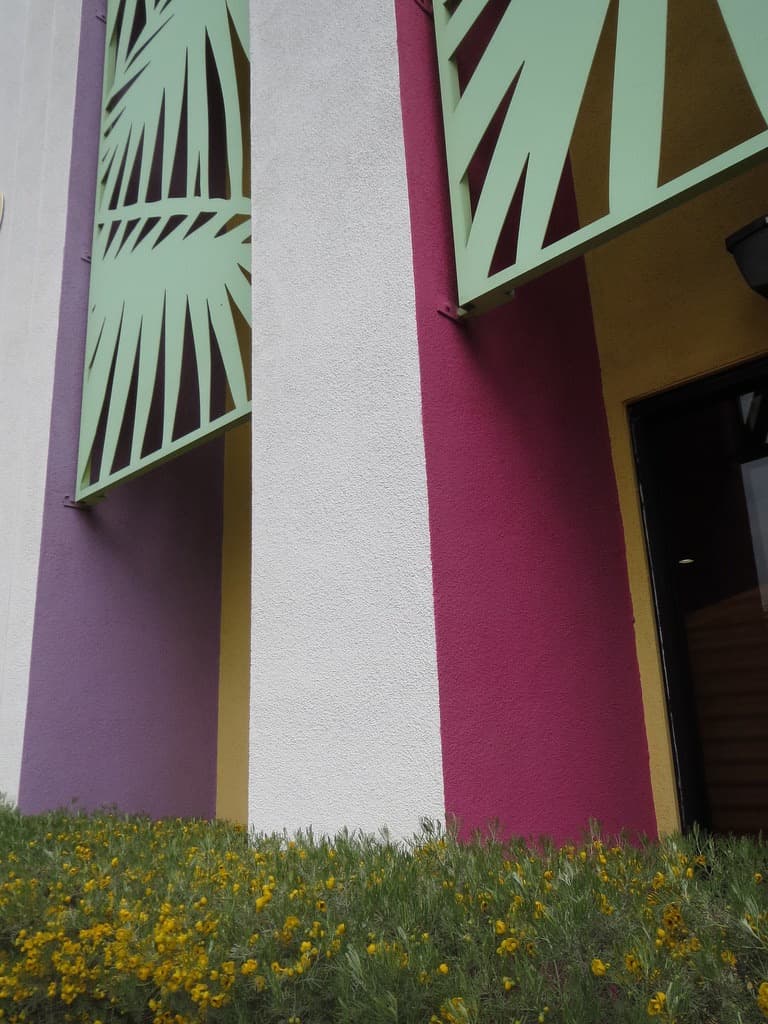 Purple, magenta and yellow color-block columns with palm-frond sunshades