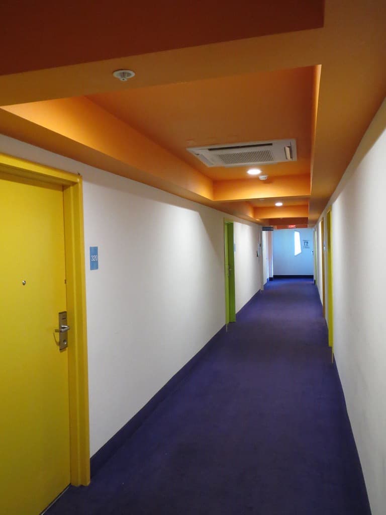 Corridor of yellow and green guest-room doors over purple carpet